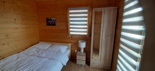niewielka sypialnia z łóżkiem i oknem w obiekcie ZIELONA DOLINA - kompleks dla rodzin z dziećmi w mieście Mikołajki