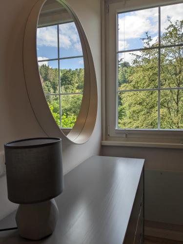 a circular mirror in a room with a table and window at Ruhiges Ferienhaus mit Sauna: Hellaberg III in Langenbach