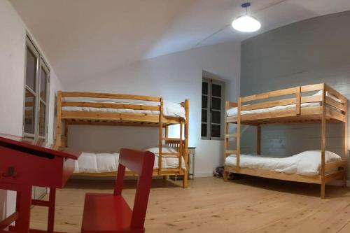 Cette chambre comprend 2 lits superposés et une chaise rouge. dans l'établissement Grand gîte au cœur des Pyrénées - Ariège Mijanes, à Mijanès