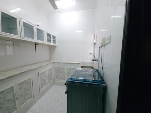 uma cozinha com paredes brancas e um armário verde em أجاويد Ajaweed em Salalah
