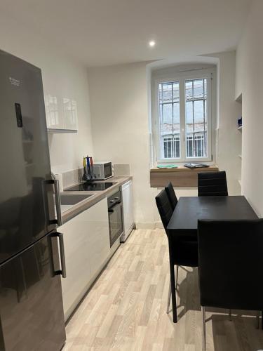 une cuisine avec une table et une table et des chaises noires dans l'établissement Bel appartement Voiron centre, à Voiron