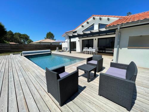 eine Terrasse mit Stühlen und einem Pool in der Unterkunft Villa Pura Vida in Magescq