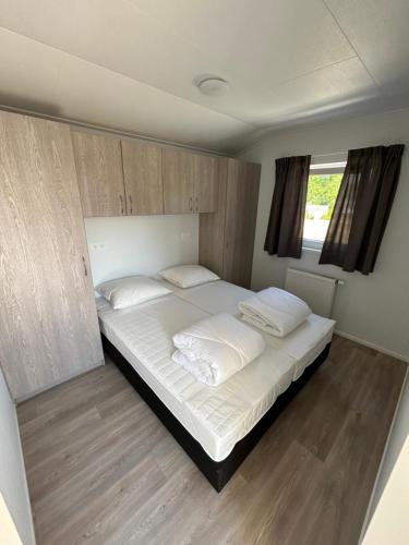 a bedroom with a large bed with white sheets and pillows at Breezy Beach Chalet in Petten