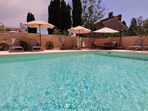ein großer Pool mit Stühlen und Sonnenschirmen in der Unterkunft Apartmani Gržinić in Rovinj