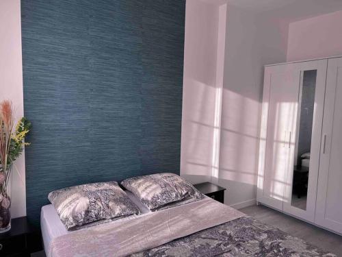 een slaapkamer met een bed en een blauwe muur bij Bel appartement en centre-ville in Le Blanc-Mesnil