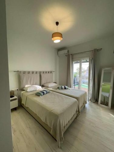 a bedroom with two beds and a large window at Boboli Holiday House Acharavi Corfu in Acharavi