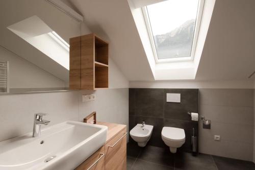 a bathroom with a sink and a toilet and a skylight at Casa Pina Campo Tures in Campo Tures