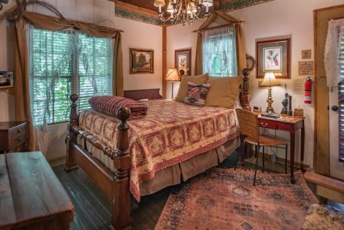 1 dormitorio con cama, mesa y ventanas en Country Woods Inn en Glen Rose