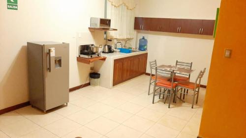 cocina con nevera, mesa y sillas en 102 RV APARTMENTS IQUITOS-APARTAMENTO FAMILIAR CON PISCINA, en Iquitos