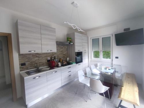 eine Küche mit weißen Schränken sowie einem Tisch und Stühlen in der Unterkunft Tirano Express Apartments in Tirano