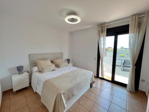 Villa Do Juano في لاجاريس: غرفة نوم بيضاء مع سرير ونافذة كبيرة