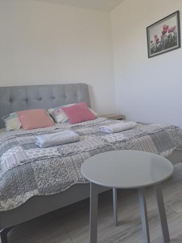 a bed with a white table and a white table at Apartament Roztocze in Zamość