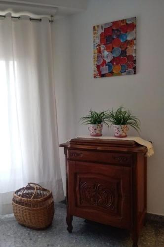 a wooden cabinet with two potted plants on it next to a window at Home S in Olavarría