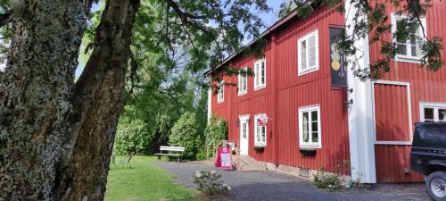 a woman in a pink dress standing next to a red barn at B&B Sunnemoslantliv in Sunnemo