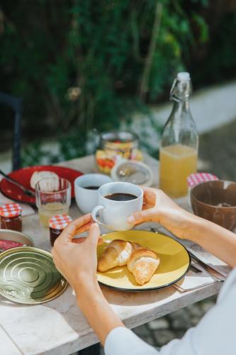 a person holding a cup of coffee and a plate of food at Senhora do Cabo Meco Homy Holidays in Sesimbra