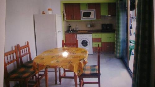 uma cozinha com uma mesa e cadeiras e um frigorífico em Roquetas de mar em Roquetas de Mar