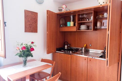 una cocina con armarios de madera y una mesa con un jarrón de flores en Casa Zu Peppino, en Lipari