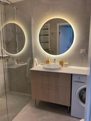 a bathroom with a sink and a shower and a mirror at Apartament PLAŻOWY 214 - Rezydencja Niechorze in Niechorze