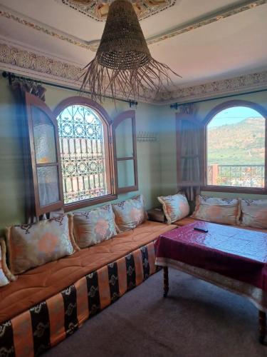 a large couch in a room with two windows at Dar rachid ouzoud in Azilal