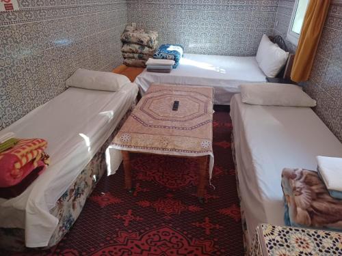 a room with two beds and a table in it at Dar rachid ouzoud in Azilal