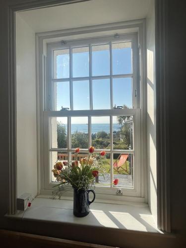 a window with a vase of flowers on a window sill at 2a Coastguard Cottages in Gorran Haven