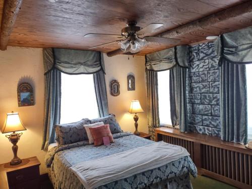 a bedroom with a bed with a ceiling fan and windows at The King George Inn in Cobourg