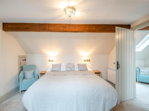 a bedroom with a large white bed and two blue chairs at The Stables Cottage in Hemingby