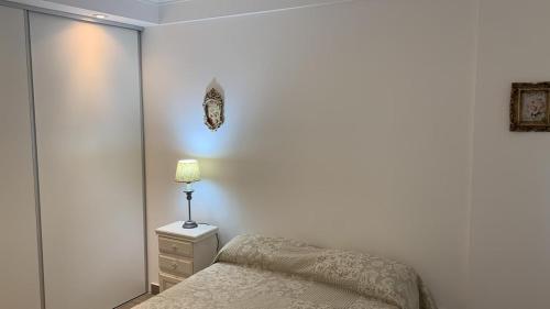 a bedroom with a bed and a lamp on a night stand at Las Acacias Tandil in Tandil