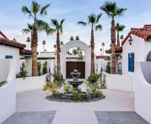 a courtyard with a fountain in front of a house with palm trees at La Serena Villas in Palm Springs