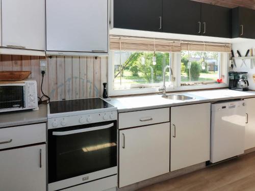 een keuken met witte kasten en een fornuis met oven bij Holiday home Storvorde XXIII in Storvorde
