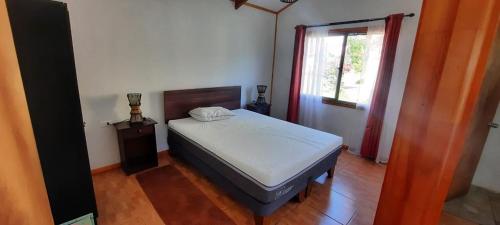 1 dormitorio con cama y ventana en cabañas Honu iti, en Hanga Roa