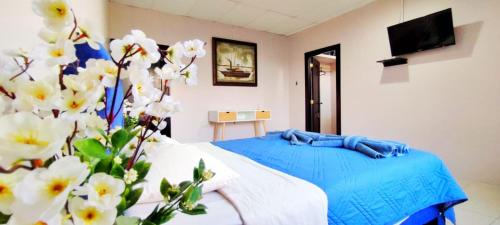 Schlafzimmer mit einem Bett mit blauer Bettwäsche und weißen Blumen in der Unterkunft Bahía Gardner in Puerto Baquerizo Moreno