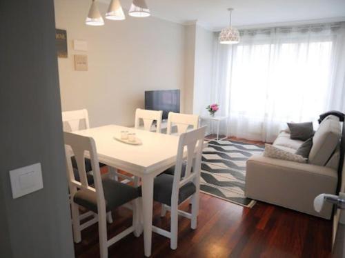 een witte eettafel met stoelen en een bank bij Concheira Deluxe, precioso apartamento in Baiona