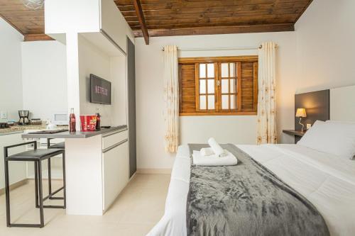a white bedroom with a bed and a desk at Chalé Mantiqueira - Cunha in Cunha