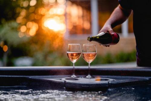 a person pouring wine into two glasses on a table at Chalet Memphrémagog (Spa, étang, golf) in Mansonville