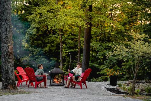 a group of people sitting around a fire in a park at Chalet Memphrémagog (Spa, étang, golf) in Mansonville