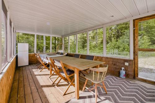comedor con mesa y sillas en el porche en Chalet Memphrémagog (Spa, étang, golf), en Mansonville
