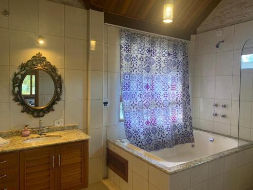 a bathroom with a tub and a shower curtain at Chalé na Av. Principal de Monte Verde com Lareira e Banheira in Camanducaia