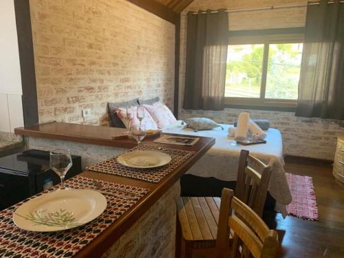 um quarto com uma cama e uma mesa com pratos e copos em Chalé na Av. Principal de Monte Verde com Lareira e Banheira em Camanducaia