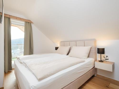 ein weißes Schlafzimmer mit einem großen Bett und einem Fenster in der Unterkunft Ski-Nature Apartment Lungau in Mauterndorf