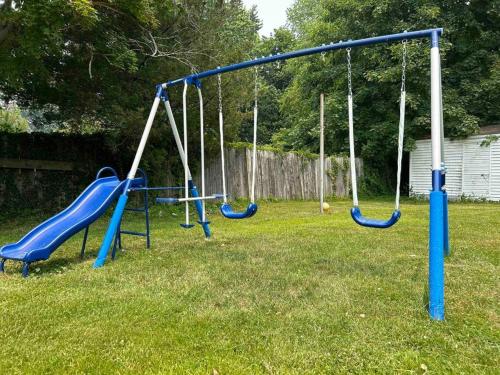 a playground with blue swings in a yard at Charming 6BR 2 Ba Secluded Retreat walk to the shore in Long Branch