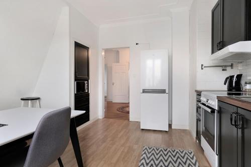 a white kitchen with a table and a white refrigerator at Guestly Homes - 4BR Charming Apartment in Piteå
