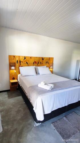 a bedroom with a large bed with a wooden headboard at Pousada Siriba in Caravelas