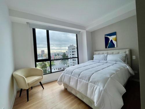 ein Schlafzimmer mit einem weißen Bett und einem großen Fenster in der Unterkunft ItsaHome Selection - Torre Renua 9C in Quito