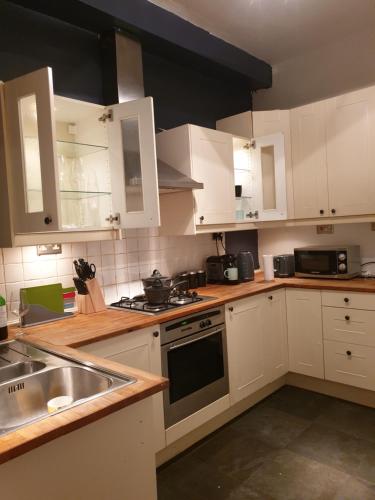 a kitchen with white cabinets and a sink at Derby rooms by Peartree in Derby