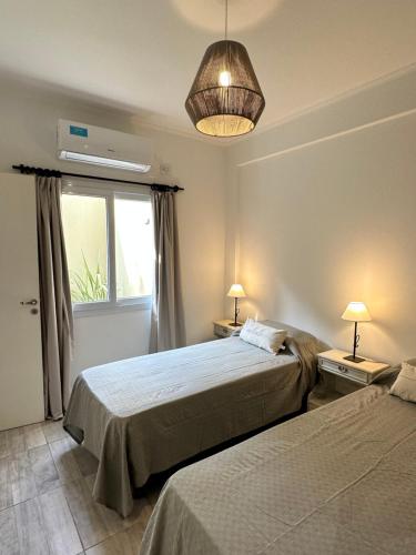 1 Schlafzimmer mit 2 Betten, einem Fenster und einer Lampe in der Unterkunft Excelente Departamento con patio in Salta