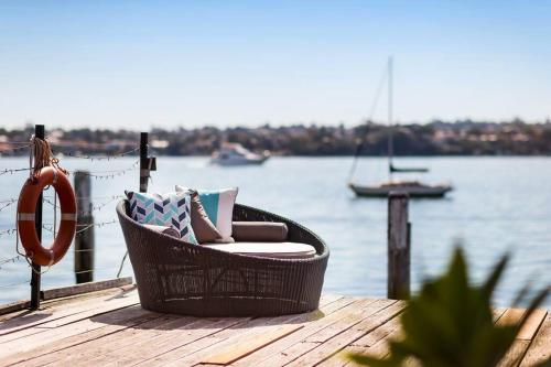 a wicker chair sitting on a dock near the water at Sydney Harbourfront Boathouse and Studio Escape in Sydney