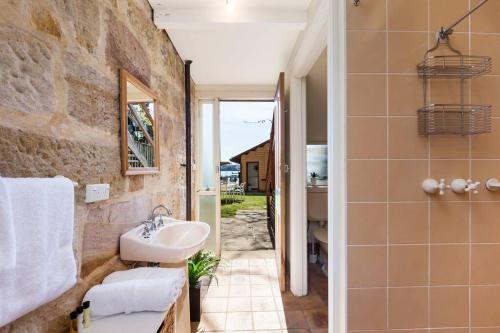 a bathroom with a sink and a stone wall at Sydney Harbourfront Boathouse and Studio Escape in Sydney