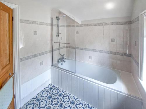 a bathroom with a tub and a tiled floor at Framingham in South Hayling