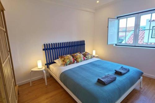 een slaapkamer met een bed met blauwe lakens en een raam bij Mouraria Lisbon Soul Apartments T2 - 5pax in Lissabon